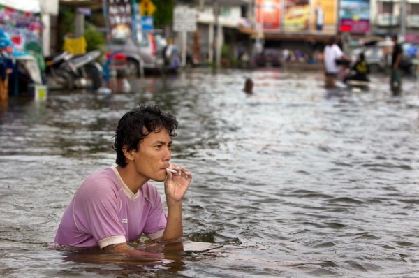 Người đàn ông hút điếu thuốc lá trong trận lụt