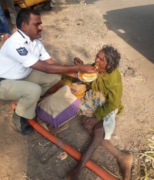   Một cảnh sát giao thông cho một người phụ nữ vô gia cư ăn ở Ấn Độ  