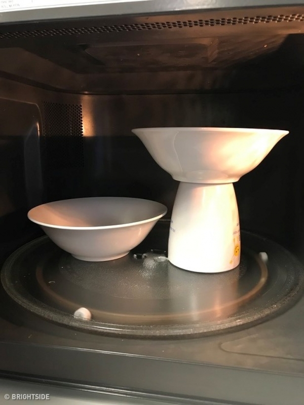 Để làm nóng 2 đĩa cùng một lúc, chỉ cần đặt đĩa đầu tiên lên đĩa vi sóng đẩy sang một bên, sau đó đặt một  cốc cà phê ngược xuống bên cạnh và đặt đĩa thứ hai lên trên cốc