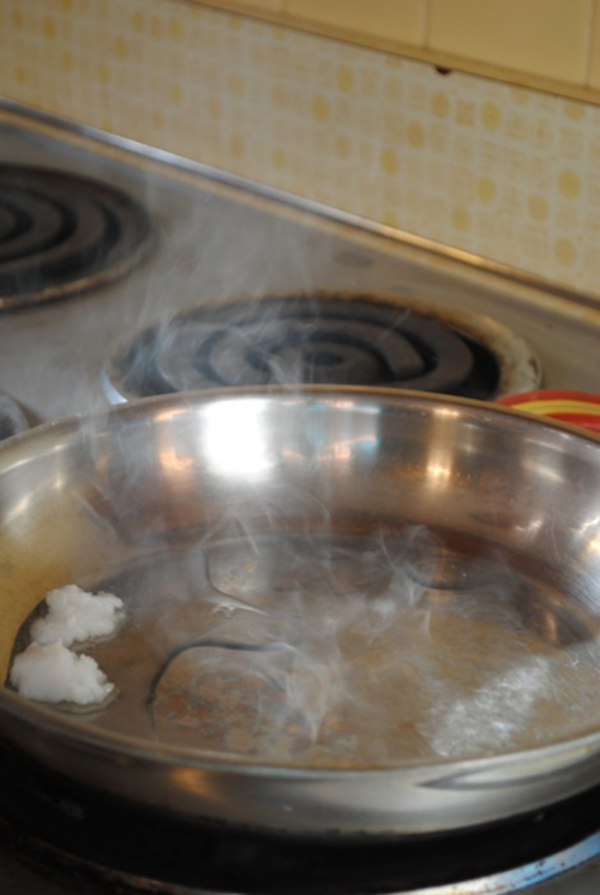Cho 2 muỗng dầu dừa vào chảo, cầm cán chảo nghiêng đều để dầu phủ kín bề mặt chảo trong 30 giây. 