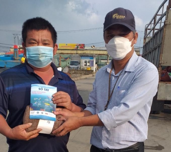 Đại diện Ban Quản lý Âu thuyền và Cảng cá Thọ Quang gửi đến ngư dân sổ tay và quà tặng của dự án. Ảnh: HN.