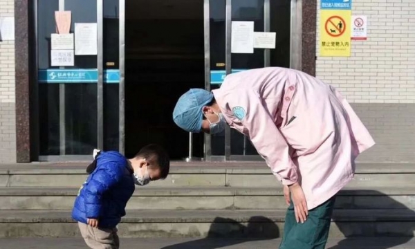 Cậu bé cúi người cảm ơn cô y tá trước cổng bệnh viện