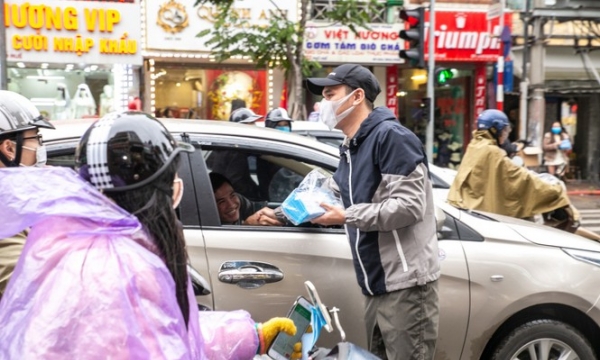 Khắc Việt đội mưa đứng phát khẩu trang cho người dân đi đường