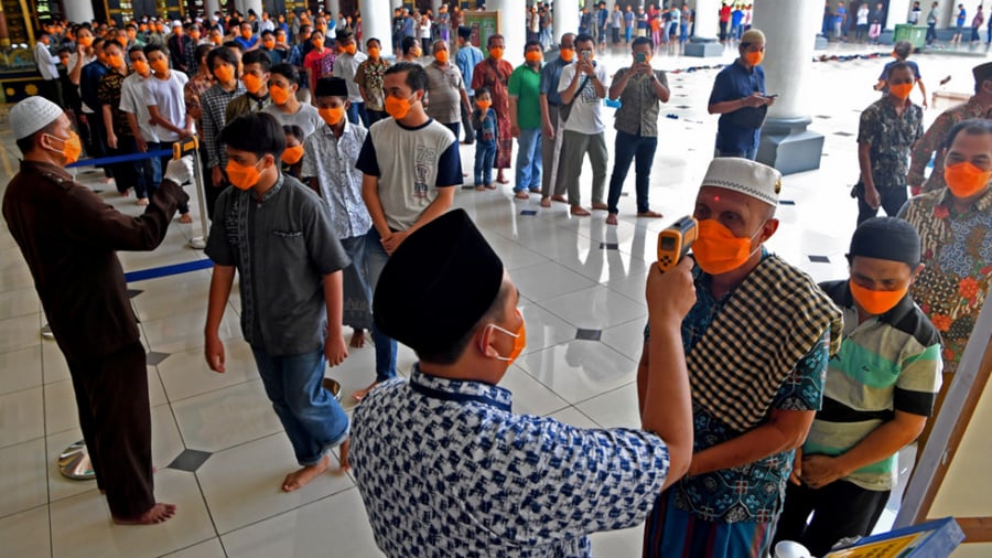 Người dân Indonesia được kiểm tra thân nhiệt trước khi vào cầu nguyện tại một nhà thờ Hồi giáo ở Surabaya, tỉnh Đông Java, Indonesia ngày 20/3
