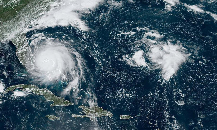 Ảnh vệ tinh ngày 2/9 từ Cơ quan Đại dương và Khí quyển Mỹ (NOAA) cho thấy bão Dorian (trái) đang “làm mưa làm gió” tại Bahamas.