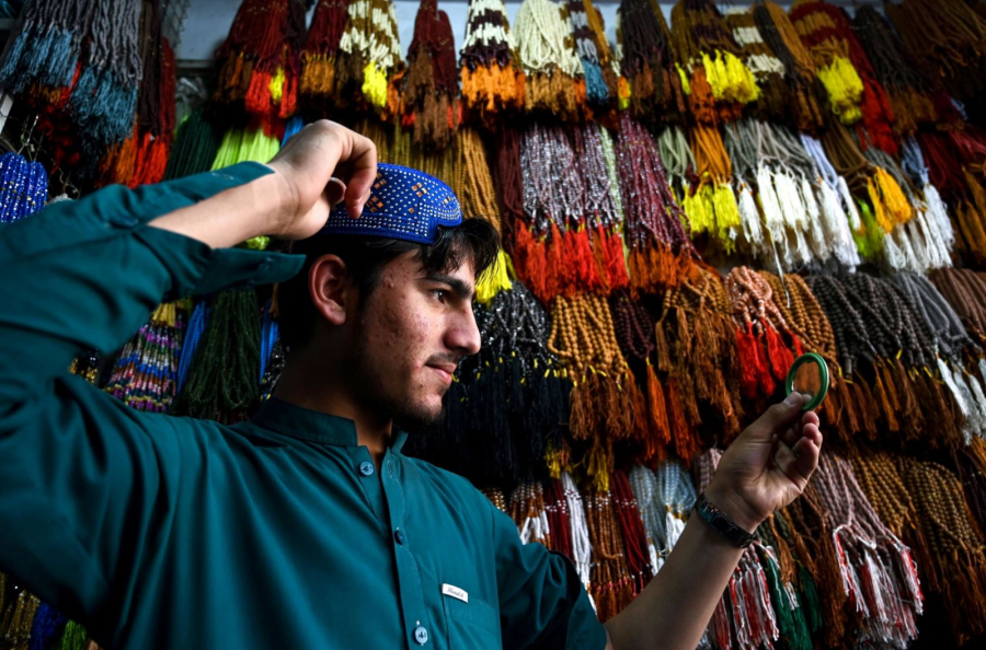 Một người Hồi giáo Pakistan tạo dáng khi anh ta thử một chiếc mũ cầu nguyện truyền thống tại một cửa hàng ở Rawalpindi 