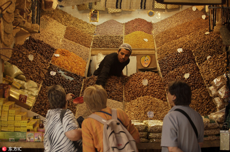 Khách du lịch được người bán hàng cho nếm thử một loại quả sấy khô trong khu chợ của Maroc.