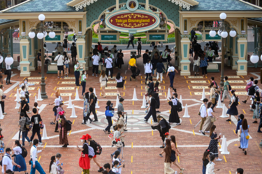 Khách đứng chờ mua vé trên vạch kẻ giãn cách ở Tokyo Disneyland ngày mở cửa