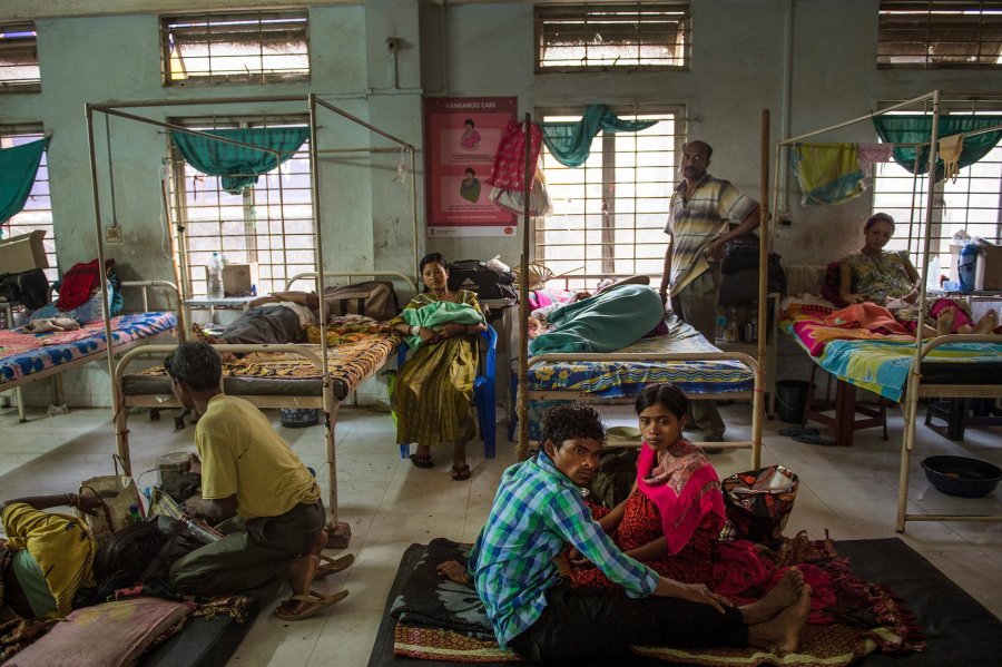 Các gia đình Ấn Độ nghỉ ngơi trong một khu dành riêng cho phụ nữ hồi phục sau sinh mổ tại bệnh viện Tezpur. Assam có tỷ lệ mẹ tử vong cao nhất ở Ấn Độ. Nhiều cơ sở y tế công cộng quá đông đúc và mất vệ sinh, bị thiếu bác sĩ có kinh nghiệm lâu năm và thường có bệnh nhân nằm ngổn ngang trên sàn nhà và ngoài hành lang. (Ảnh: Maternal Mortality - Lynsey Addario)