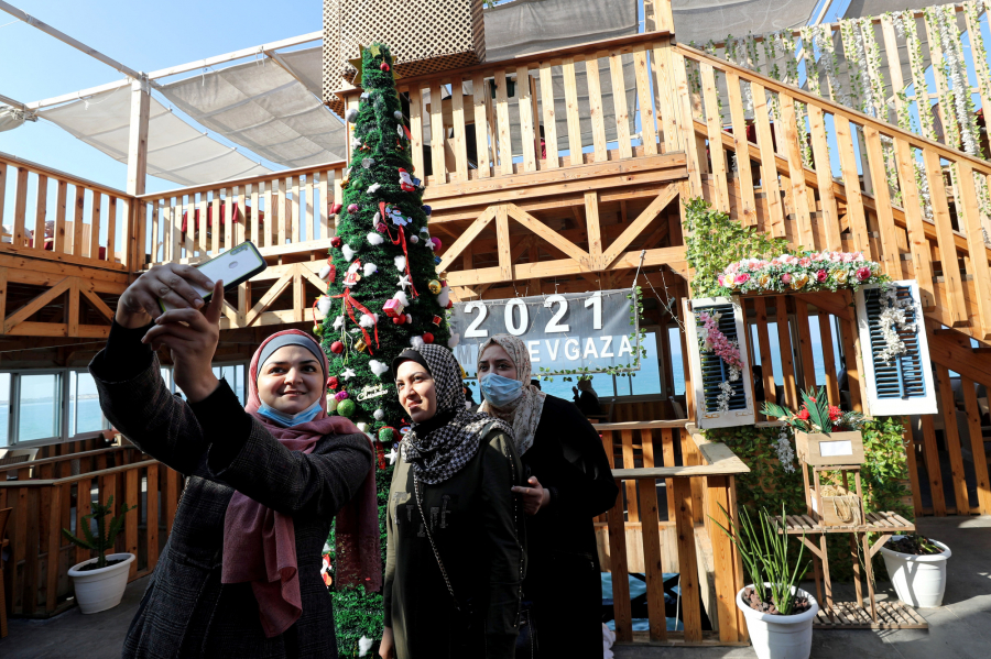 Hai người phụ nữ Palestine chụp hình trước cây thông Noel ở một quán cà phê trong thành phố Gaza ngày 21/12