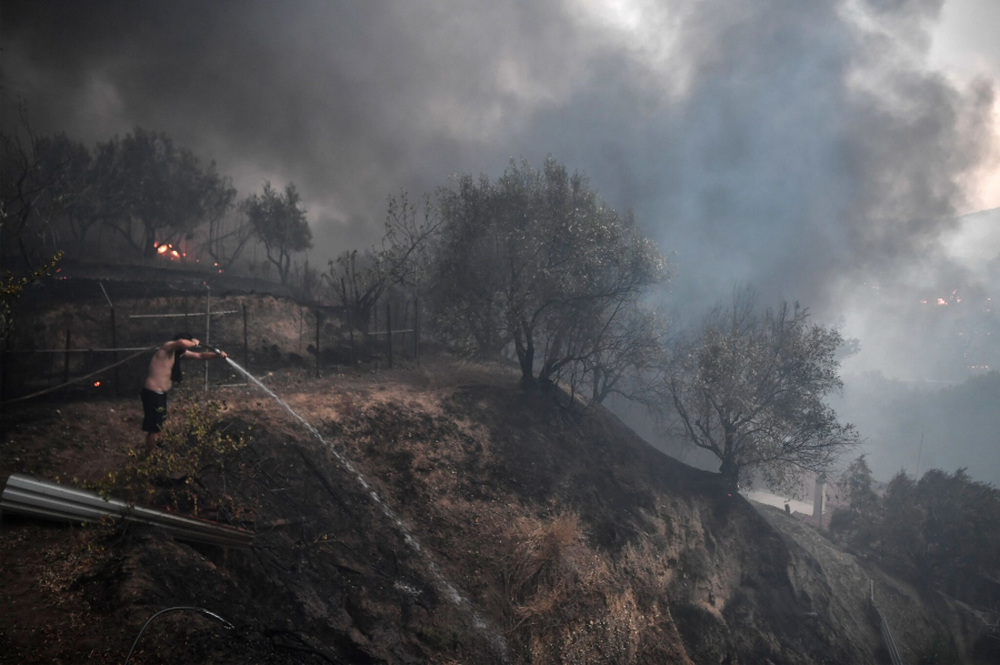 Nhân viên cứu hỏa cố gắng dập tắt đám cháy ở sân một ngôi nhà trong rừng Dekelia-Tatoi, ngoại ô Athens. (Ảnh: Louisa Gouliamaki/Agence France-Presse - Getty Images)