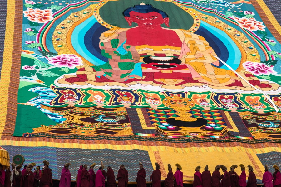 Các nhà sư mở ra thangka mô tả Đức Phật để trưng bày cho những người thờ phượng và những du khách khác trong lễ hội.