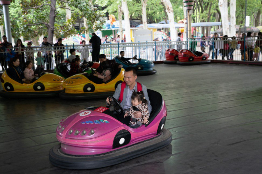 Zhang Yuewei và bố cố bé đang chơi xe điện đụng trong công viên. 