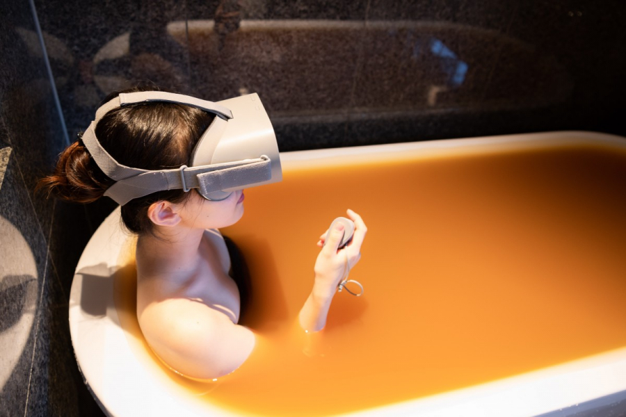 Một nhân viên của Arima Onsen đang thử trải nghiệm thực tế ảo bằng VR Headset trong bồn tắm đầy nước khoáng lấy từ suối nước nóng