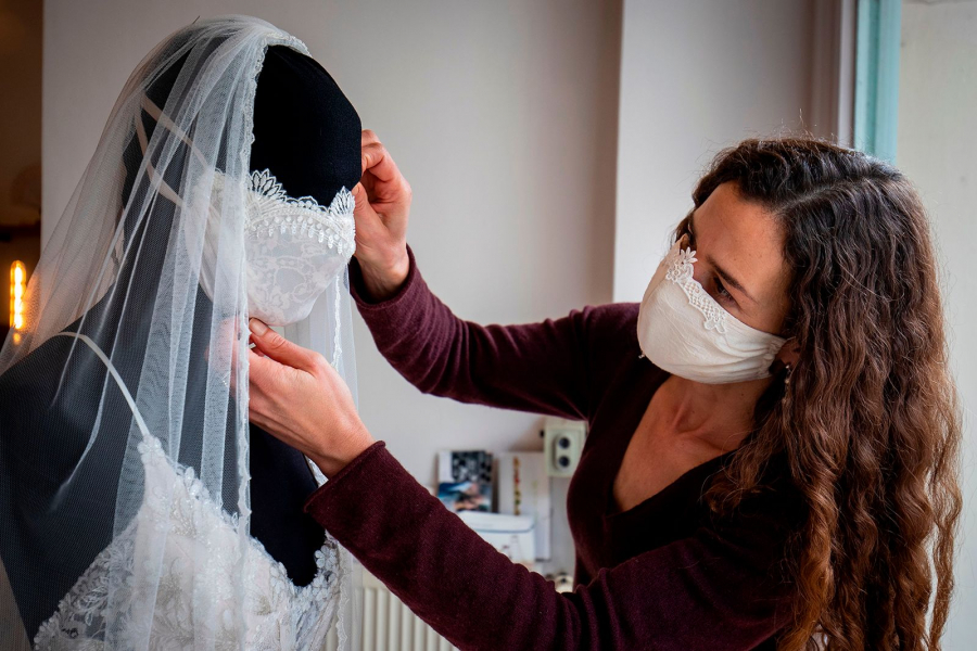 Nhà thiết kế thời trang Friederike Jorzig đang chỉnh lại chiếc khẩu trang cùng bộ với váy cưới trong cửa hàng của cô tại Berlin. (Ảnh: Odd Andersen/AFP/Getty Images)