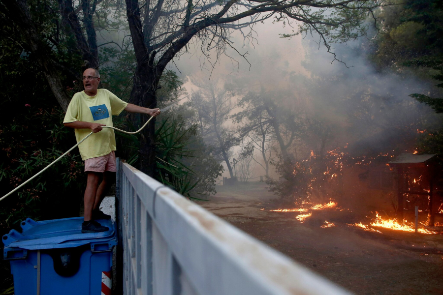 Một số người mở vòi nước muốn dập tắt ngọn lửa, cố gắng ngăn đám cháy đến gần nhà mình. (Ảnh: Yiannis Kolesidis/EPA, Shutterstock)