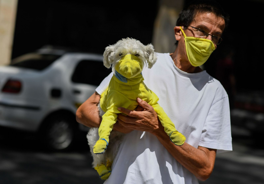 Một người đàn ông ở Caracas, Venezuela cùng với chú chó của mình diện khẩu trang đôi. (Ảnh: Federico Parra/AFP/Getty Images)