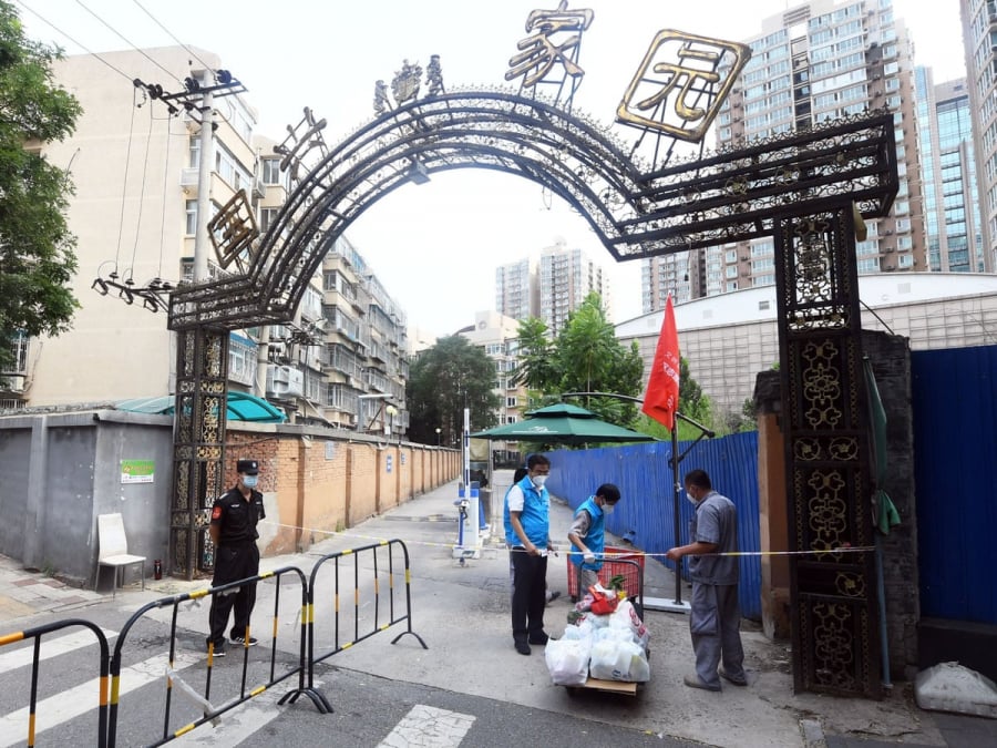 Các tình nguyện viên giao nhu yếu phẩm do người dân đặt hàng trong khu cách ly ở quận Hải Điến, Bắc Kinh - Ảnh: The Guardian