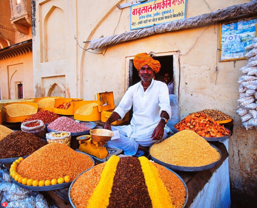 Một người bán gia vị trong chợ Amber của thành phố Jaipur, Ấn Độ với từng đụn gia vị đặc trưng của ẩm thực đất nước này như hồi, quế, thảo quả…