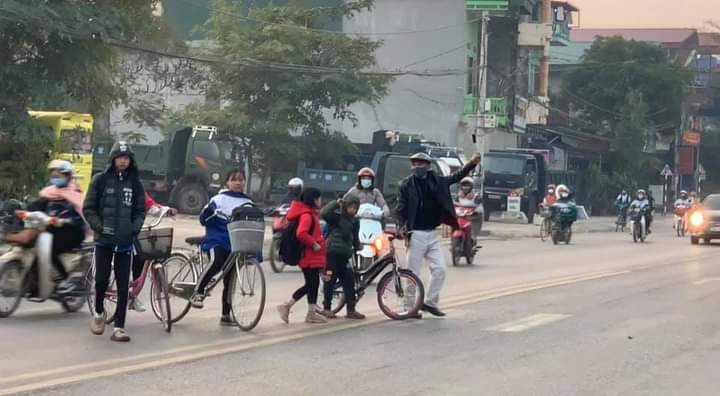 Anh Trần Hữu Tân đưa các em học sinh qua đường - Ảnh NVCC