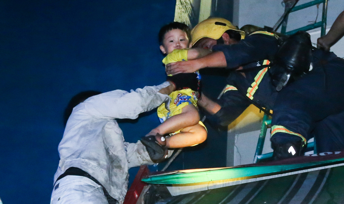 Cảnh sát dùng xe thang tiếp cận các tầng cao của chung cư Carina để đưa nhiều phụ nữ, trẻ em, người già thoát khỏi đám cháy rạng sáng 23/3/2018. Ảnh: Vnexpress