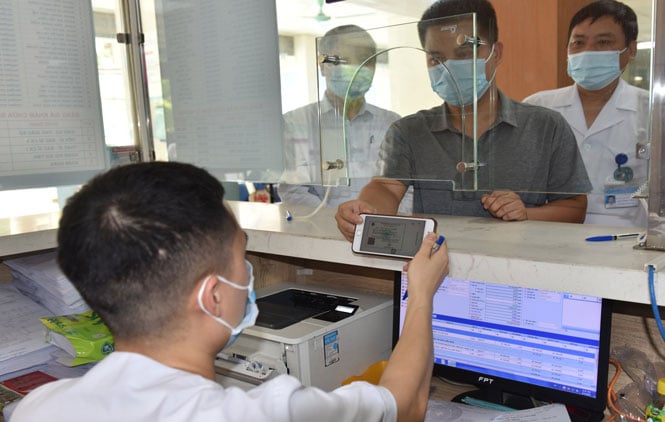 Bệnh nhân sử dụng thẻ BHYT điện tử để đăng ký khám bệnh tại Bệnh viện Đa khoa Hà Đông. Ảnh: Hà Nội Mới