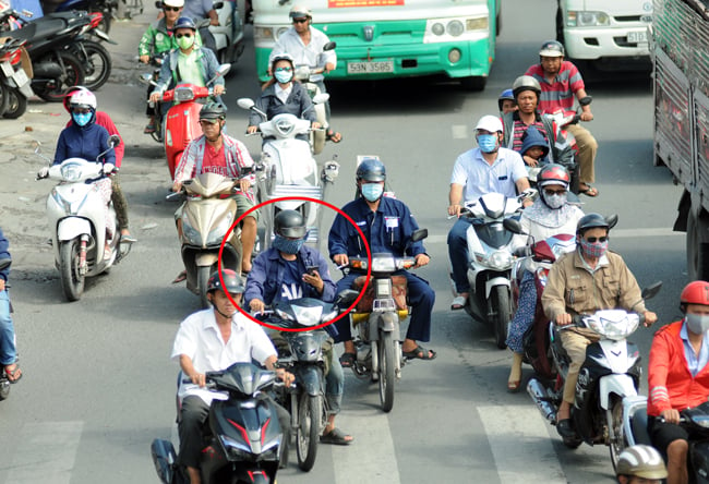 Vừa chạy xe máy vừa xem điện thoại ngày càng trở nên phổ biến trên đường phố. Ảnh: Báo Tin tức
