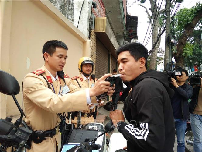 Lực lượng chức năng tiến hành đo nồng độ cồn đối với người điều khiển xe máy vi phạm tại nút giao thông Hàng Cót - Phan Đình Phùng (Ảnh: TTXVN)